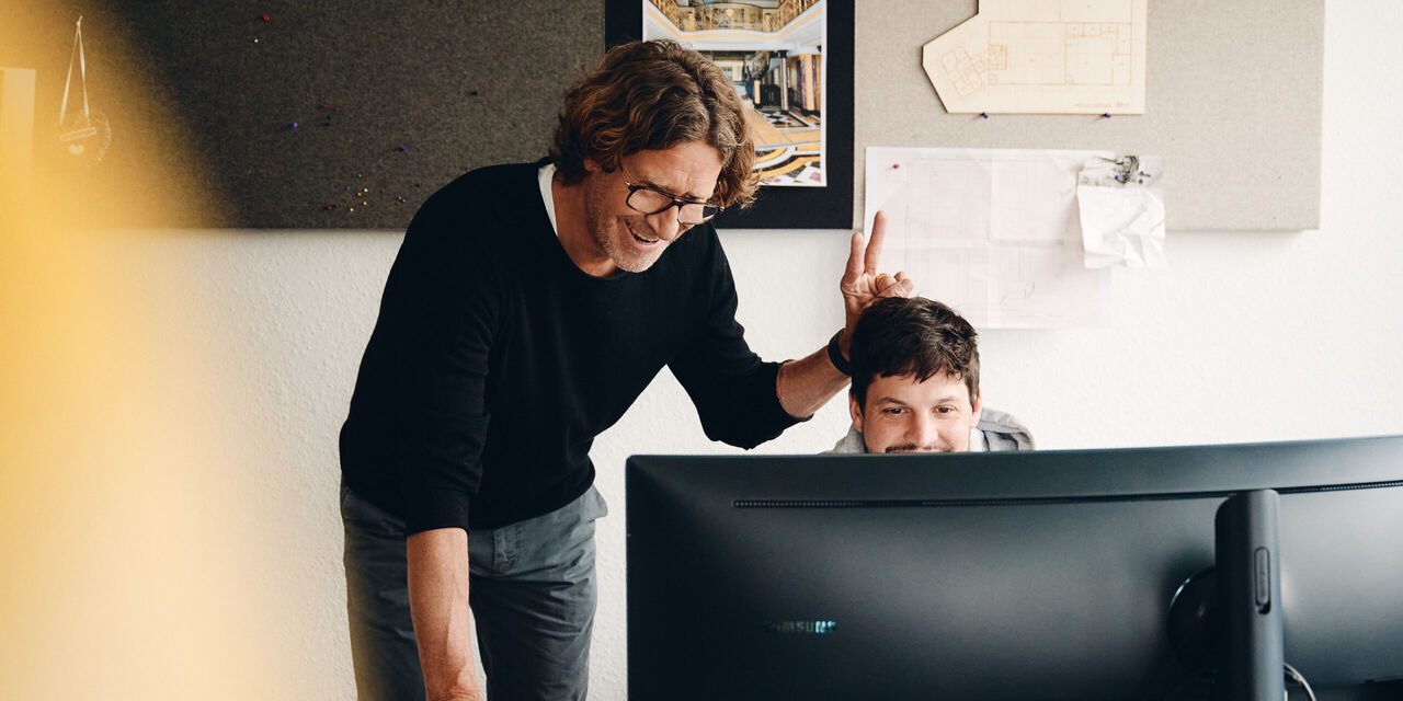 Marc und Butsch arbeiten gemeinsam am Monitor in der Werkstatt.