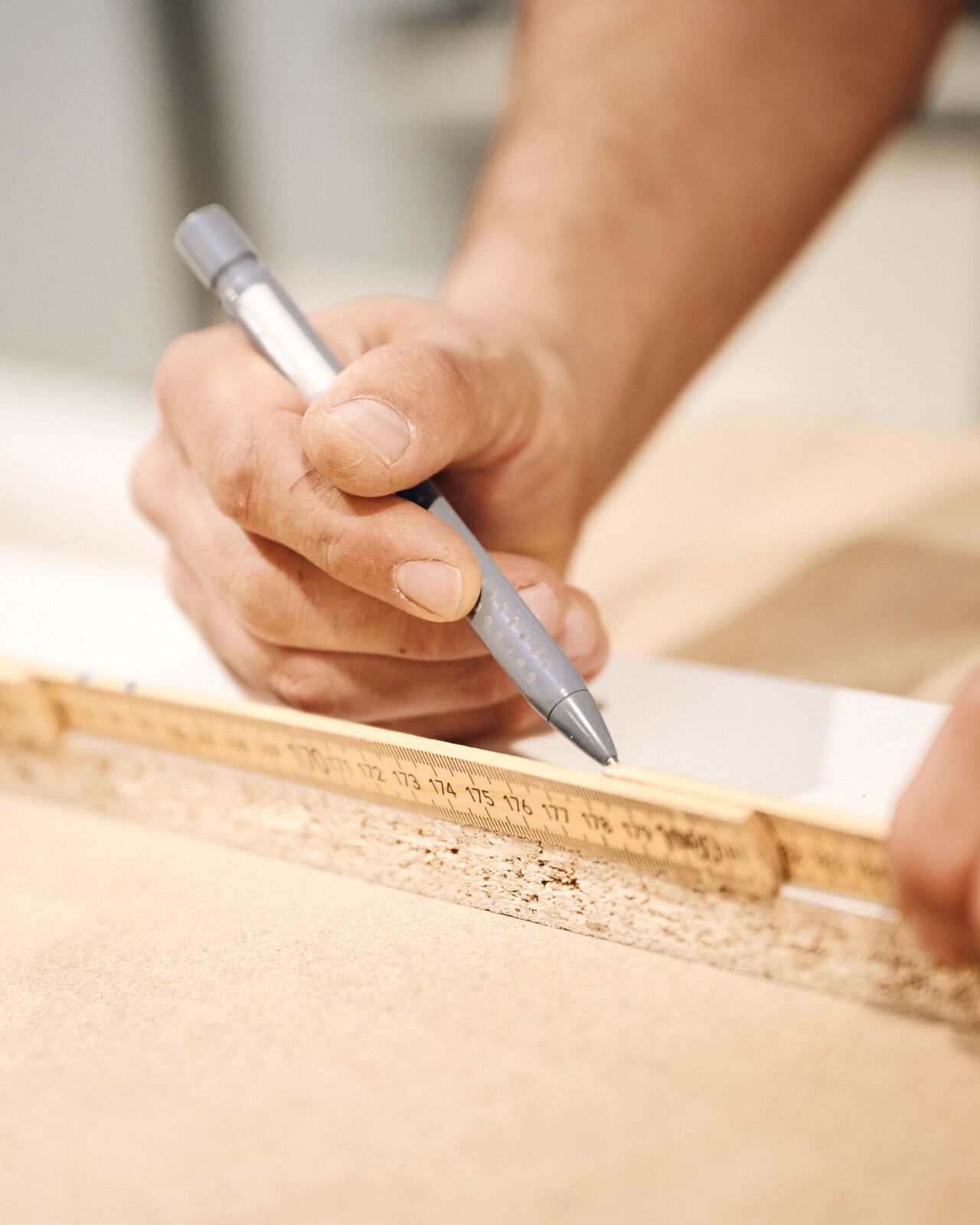Handwerker markiert Holz präzise mit einem Bleistift während der Möbelherstellung.