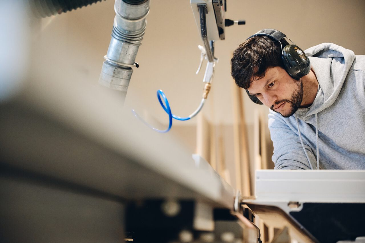 Butsch arbeitet mit Schutzbrille konzentriert an einer Maschine in der Werkstatt.